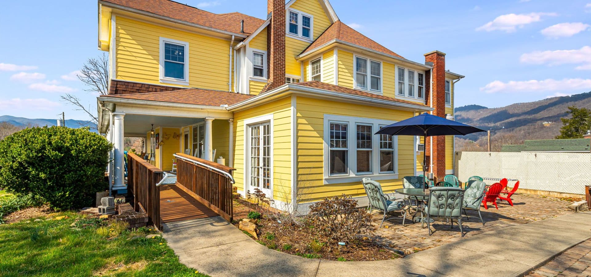 A charming yellow house with a patio and mountain views.