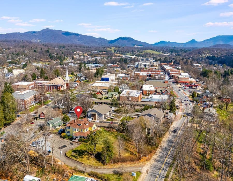 Aerial view of a town featuring mountains in the background and a highlighted house.