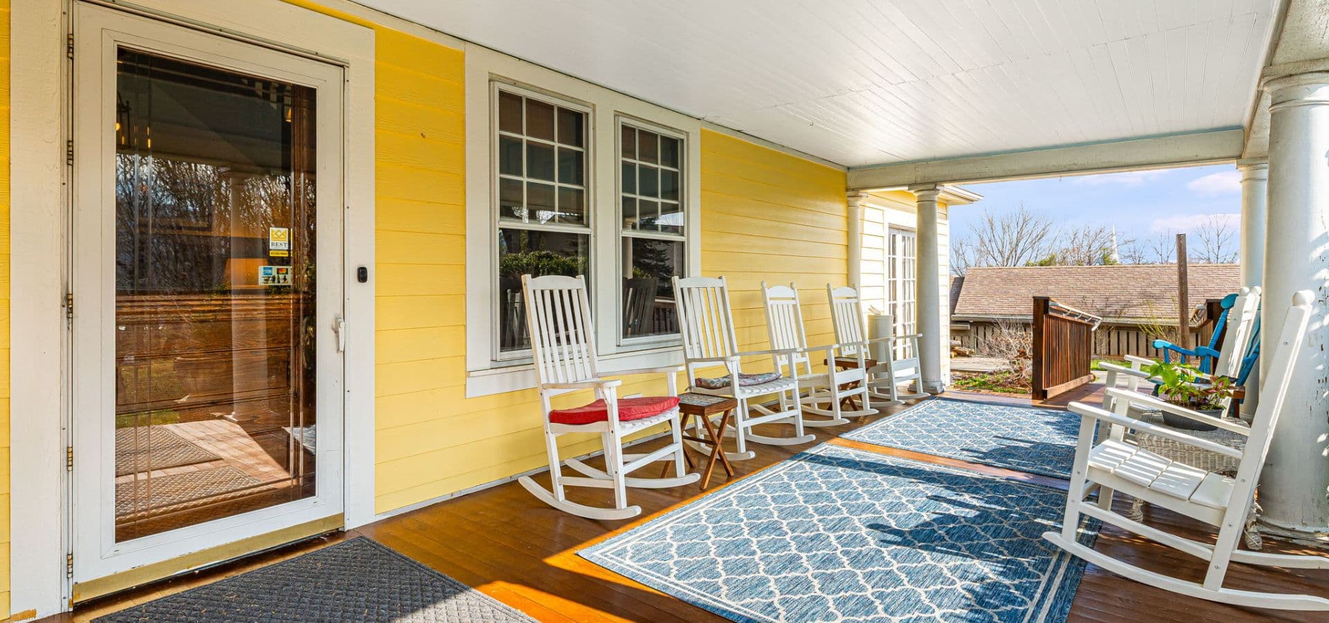 A bright yellow porch with rocking chairs and a patterned rug.